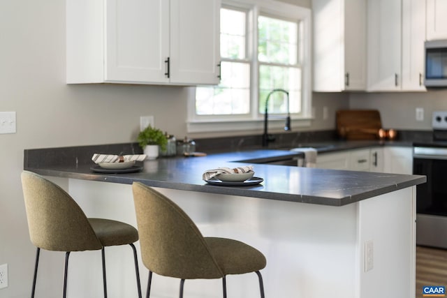 1601 Antoinette Ave, Charlottesville, VA 22903 - kitchen featuring stainless steel microwave, dark countertops, white cabinets, and a breakfast bar area