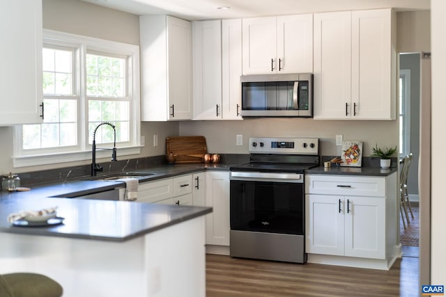 1601 Antoinette Ave, Charlottesville, VA 22903 - kitchen featuring stainless steel appliances, white cabinets, wood finished floors, and dark countertops