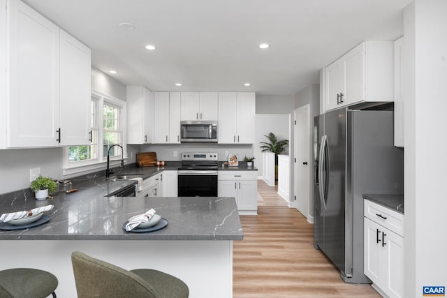 1601 Antoinette Ave, Charlottesville, VA 22903 - kitchen featuring stainless steel appliances, light wood finished floors, a peninsula, dark stone counters, and white cabinets