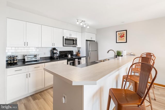 1545 Cliffs, Roseland, VA 22967 - kitchen featuring appliances with stainless steel finishes, a sink, light wood finished floors, and a breakfast bar