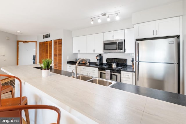 1545 Cliffs, Roseland, VA 22967 - kitchen with appliances with stainless steel finishes, a breakfast bar, white cabinetry, and decorative backsplash