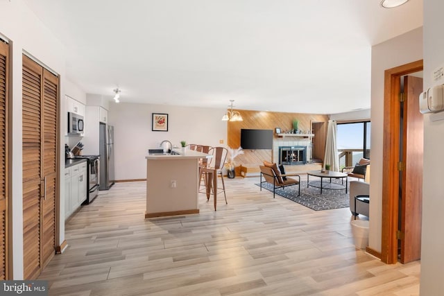 1545 Cliffs, Roseland, VA 22967 - kitchen with appliances with stainless steel finishes, white cabinetry, light wood-style floors, a kitchen breakfast bar, and wood walls