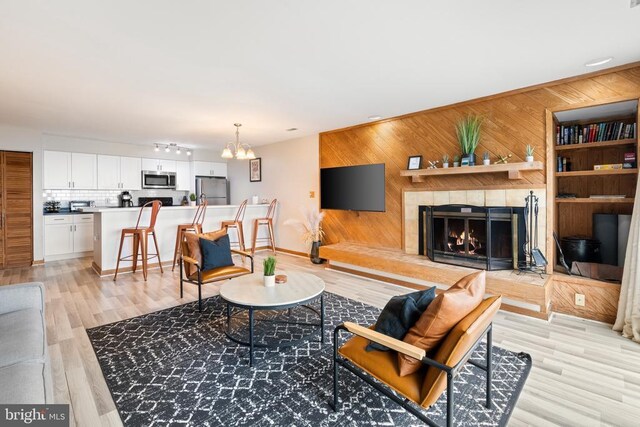 1545 Cliffs, Roseland, VA 22967 - living room with wooden walls, a chandelier, a warm lit fireplace, and light wood-style flooring