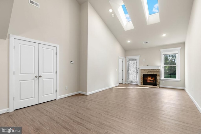 5711 Finley Rose Ct, Fredericksburg, VA 22407 - unfurnished living room featuring high vaulted ceiling, a skylight, wood finished floors, a stone fireplace, and recessed lighting