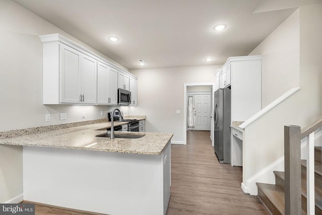 5711 Finley Rose Ct, Fredericksburg, VA 22407 - kitchen with appliances with stainless steel finishes, a peninsula, white cabinetry, wood finished floors, and recessed lighting