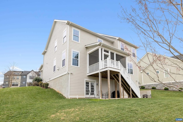 rear view of house with a lawn, a deck, stairway, and a sunroom