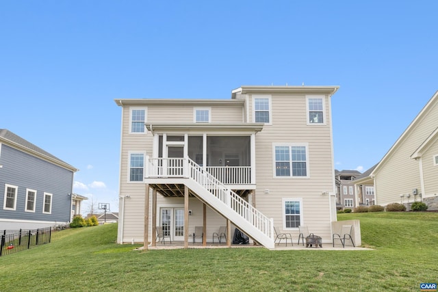 rear view of property featuring a sunroom, a patio area, an outdoor fire pit, and a lawn