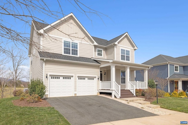 view of front of home with covered porch, driveway, a garage, a front lawn, and board and batten siding