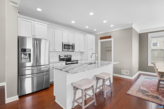 kitchen with a sink, stainless steel appliances, white cabinetry, dark wood-style flooring, and baseboards