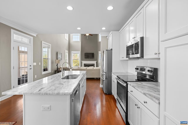 kitchen featuring a ceiling fan, a sink, a kitchen island with sink, white cabinetry, and appliances with stainless steel finishes