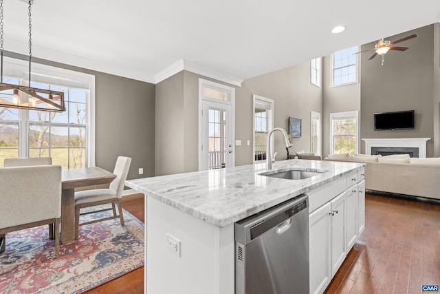 kitchen featuring a sink, a fireplace, dishwasher, light stone counters, and dark wood-style floors