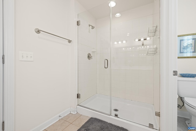 bathroom featuring toilet, baseboards, tile patterned floors, and a stall shower