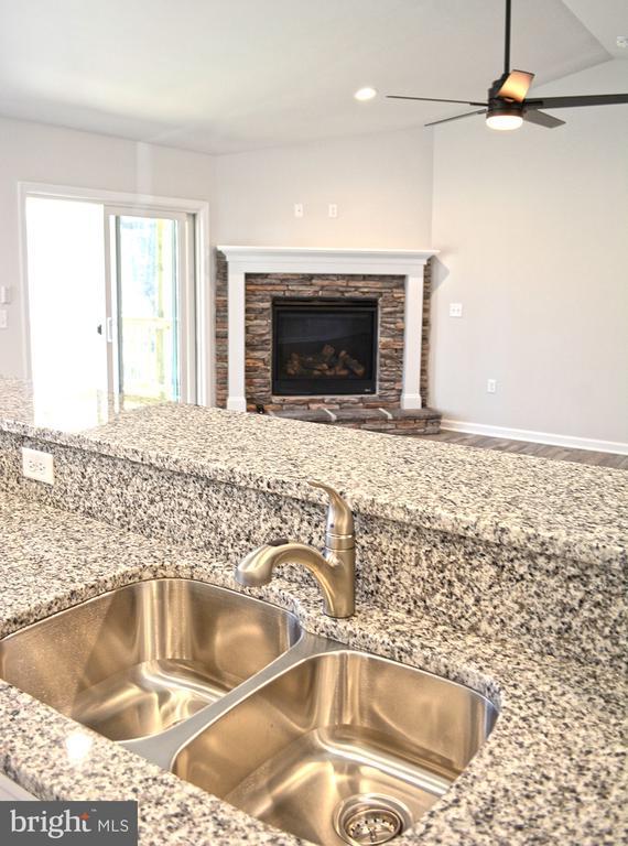 5208 Wyndemere Cir, Mineral, VA 23117 - kitchen view of a sink, a ceiling fan, a stone fireplace, wood finished floors, and light stone countertops