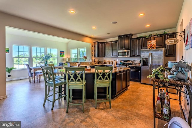 2045 Magnolia Cir, Culpeper, VA 22701 - kitchen with stainless steel appliances, a kitchen breakfast bar, an island with sink, light stone countertops, and recessed lighting