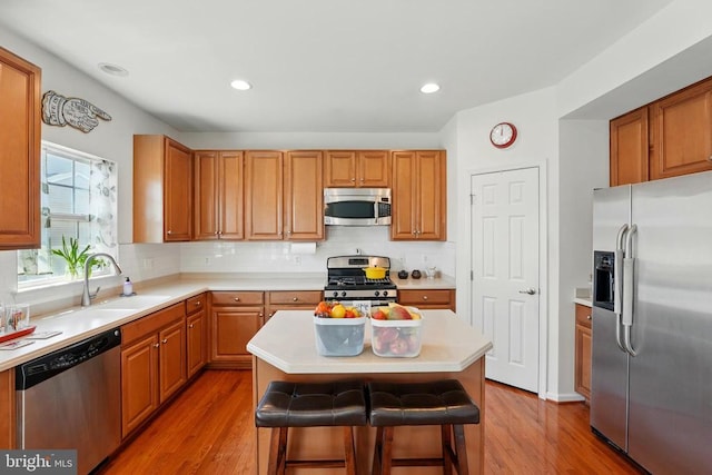 kitchen with stainless steel appliances, light wood-type flooring, light countertops, tasteful backsplash, and recessed lighting