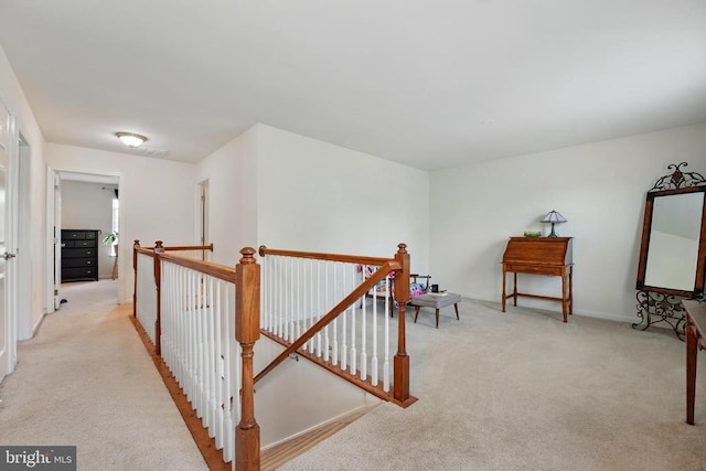 hallway with light carpet, an upstairs landing, and baseboards