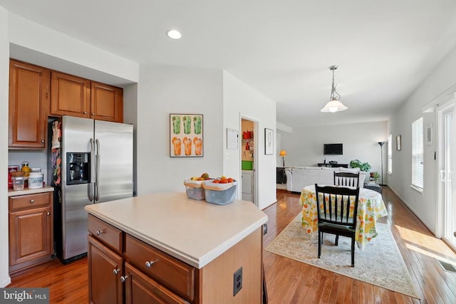kitchen featuring stainless steel refrigerator with ice dispenser, open floor plan, light wood-type flooring, light countertops, and recessed lighting