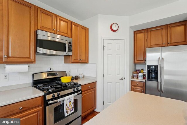 kitchen with stainless steel appliances, light countertops, decorative backsplash, and brown cabinetry