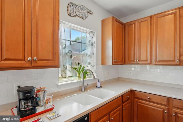 kitchen featuring a sink, light countertops, brown cabinetry, and decorative backsplash