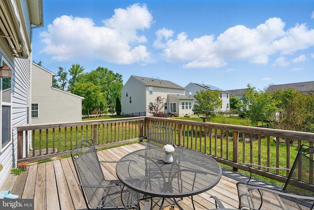 deck featuring a residential view, outdoor dining space, and a lawn