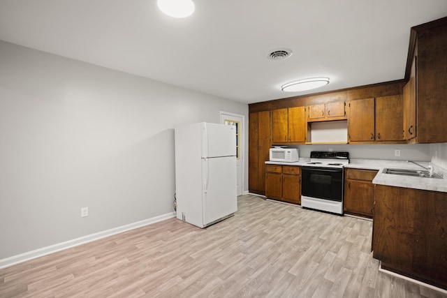 kitchen featuring sink, white appliances, and light wood-type flooring