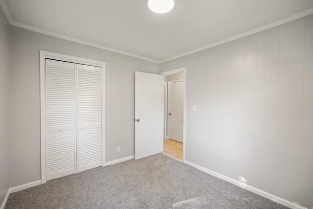 unfurnished bedroom featuring a closet, ornamental molding, and light carpet