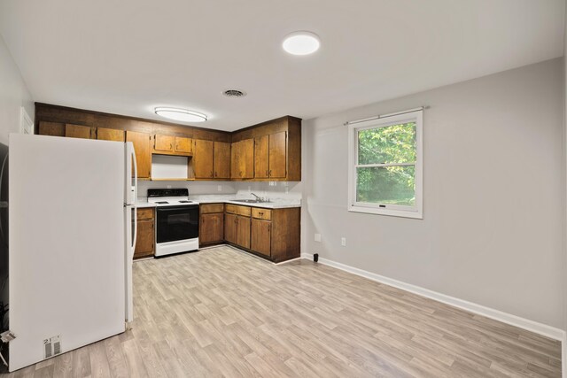 kitchen with light hardwood / wood-style flooring, sink, white fridge, and range with electric stovetop