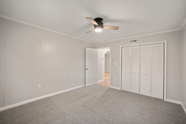 unfurnished bedroom featuring ceiling fan, ornamental molding, carpet floors, and a closet