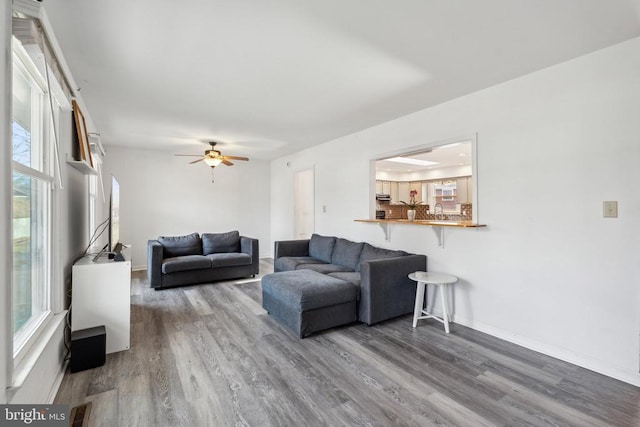 living area with ceiling fan, wood finished floors, visible vents, and baseboards