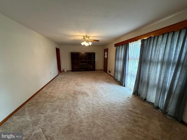 unfurnished living room with carpet, a ceiling fan, and baseboards