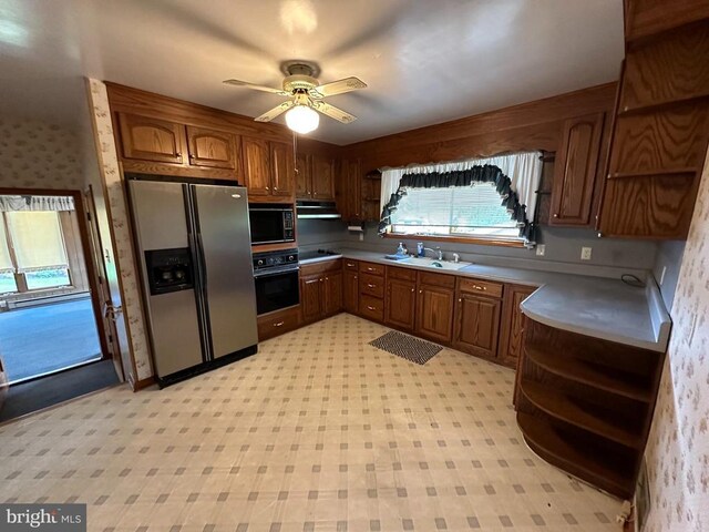 kitchen with black appliances, open shelves, a sink, light floors, and wallpapered walls