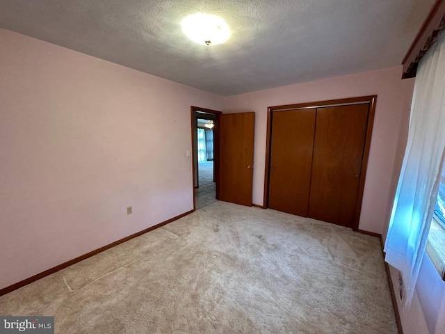 unfurnished bedroom featuring light colored carpet, a closet, and baseboards