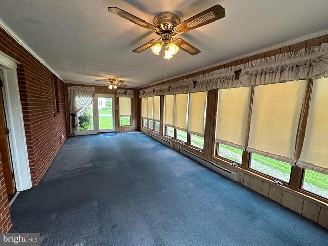 unfurnished sunroom featuring ceiling fan, brick wall, carpet, ornamental molding, and baseboard heating