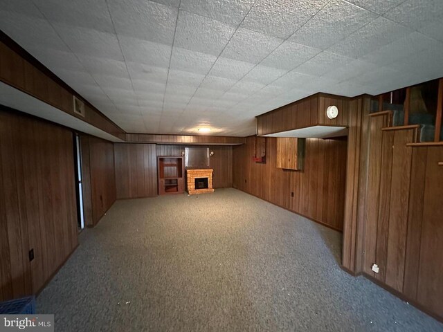 finished below grade area with wood walls, a brick fireplace, and carpet flooring