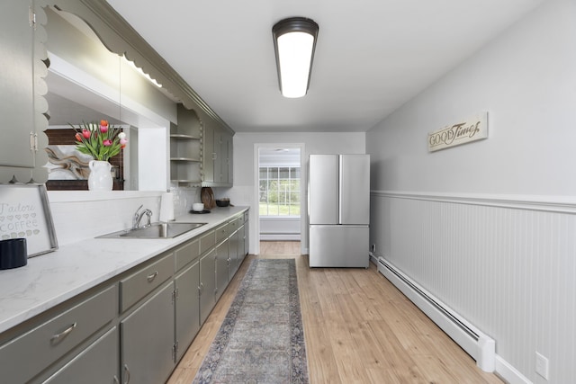 kitchen with a baseboard heating unit, freestanding refrigerator, gray cabinets, baseboard heating, and wainscoting