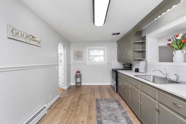 kitchen featuring gas stove, a sink, a baseboard radiator, open shelves, and arched walkways