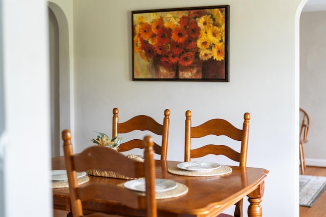 dining space with arched walkways and wood finished floors