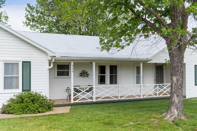 back of house featuring covered porch and a yard