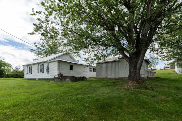 view of side of home with a lawn and metal roof