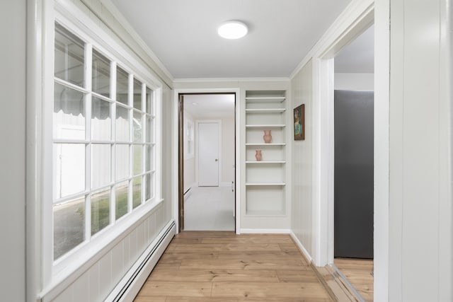 hallway featuring a baseboard heating unit, built in shelves, light wood-style floors, and ornamental molding