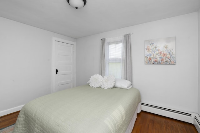 bedroom featuring wood finished floors, baseboard heating, and baseboards