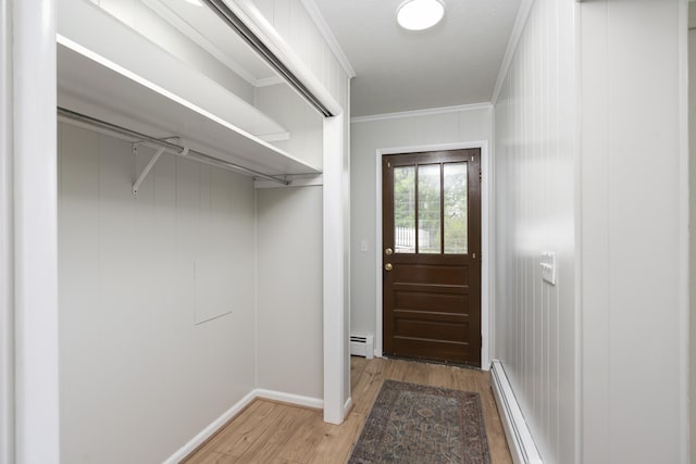 entryway with baseboard heating, a baseboard heating unit, light wood-style floors, baseboards, and ornamental molding
