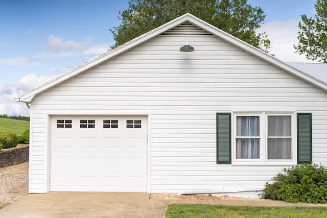 view of side of home featuring driveway, a garage, and an outbuilding