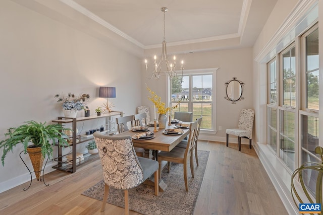 dining area with ornamental molding, a chandelier, light wood finished floors, a raised ceiling, and baseboards