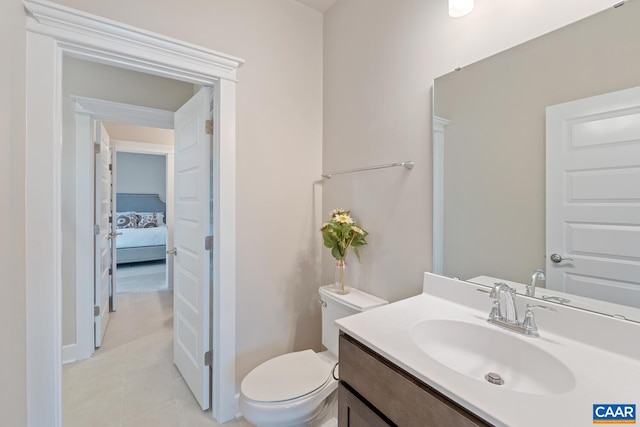 half bathroom featuring vanity, toilet, baseboards, and tile patterned floors