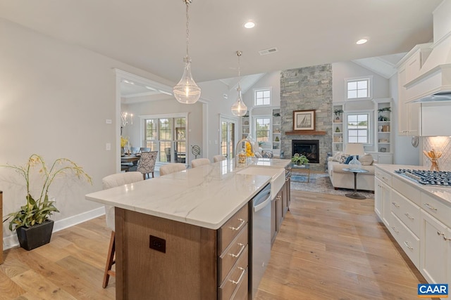 kitchen featuring a sink, a kitchen breakfast bar, white cabinets, visible vents, and vaulted ceiling