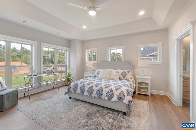 bedroom with multiple windows, visible vents, and a raised ceiling