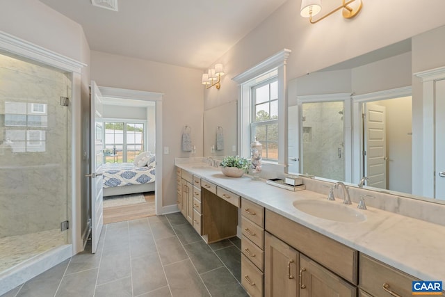 ensuite bathroom with double vanity, tile patterned flooring, a shower stall, and a sink