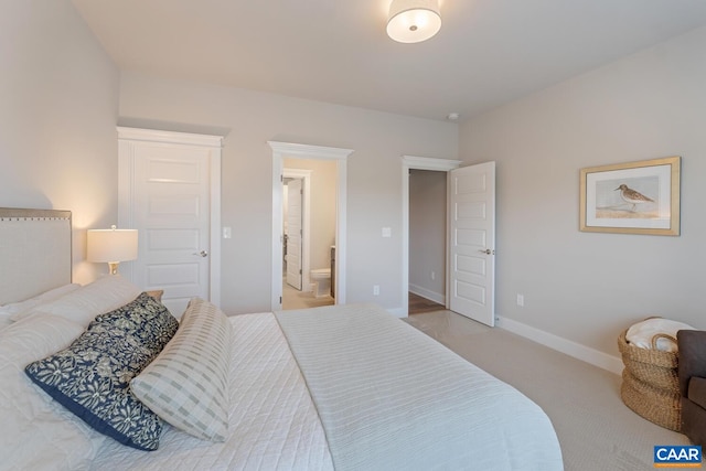 carpeted bedroom with connected bathroom and baseboards