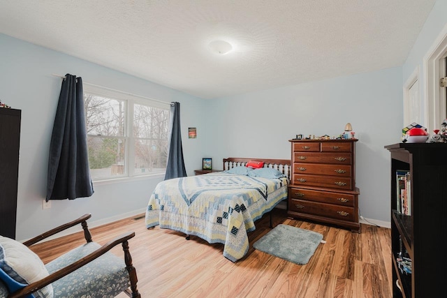 bedroom with baseboards, a textured ceiling, and wood finished floors